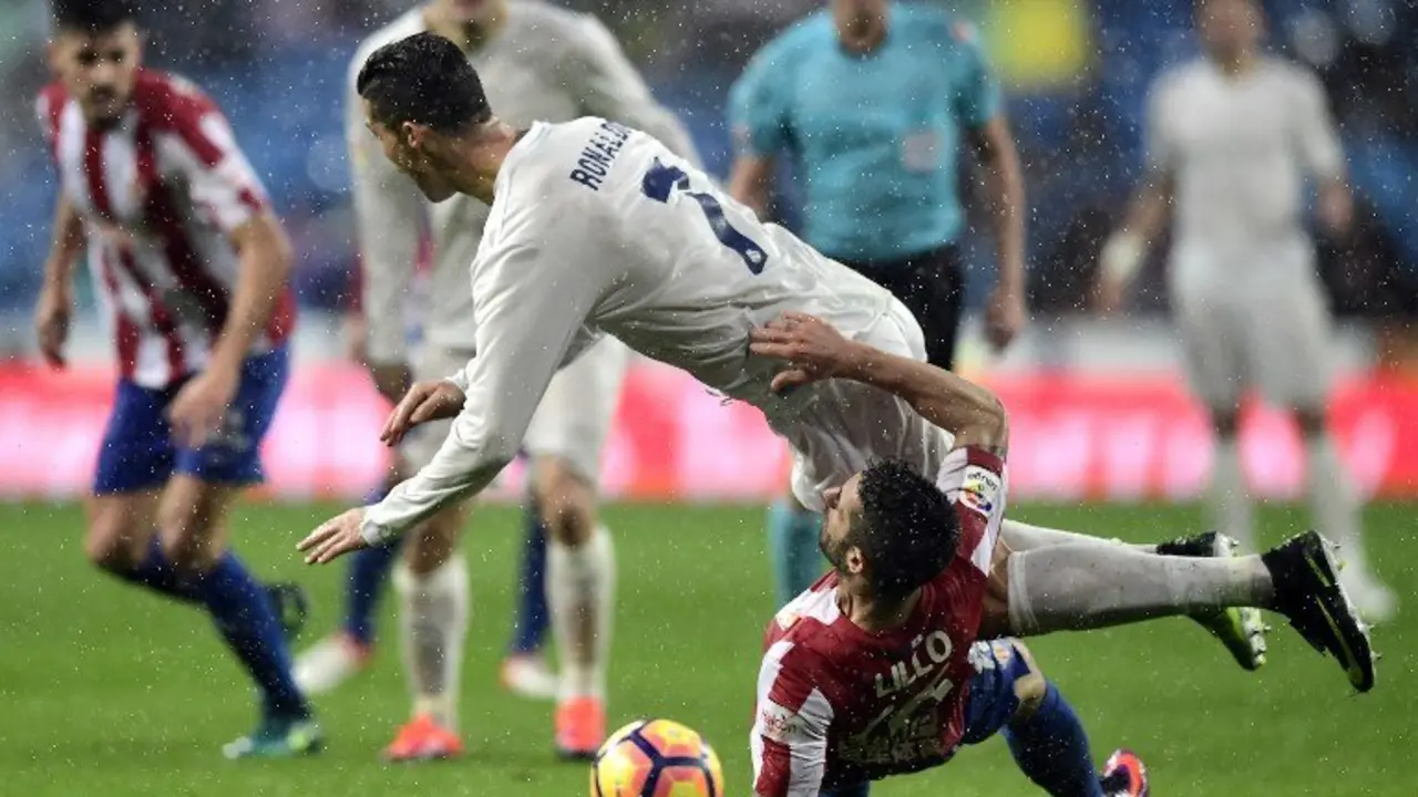 Real Madrid's Portuguese forward Cristiano Ronaldo (top) falls over Sporting Gijon's defender Lillo Castellano during the Spanish league football match Real Madrid CF vs Real Sporting de Gijon at the Santiago Bernabeu stadium in Madrid on November 26, 2016. / AFP PHOTO / JAVIER SORIANO
