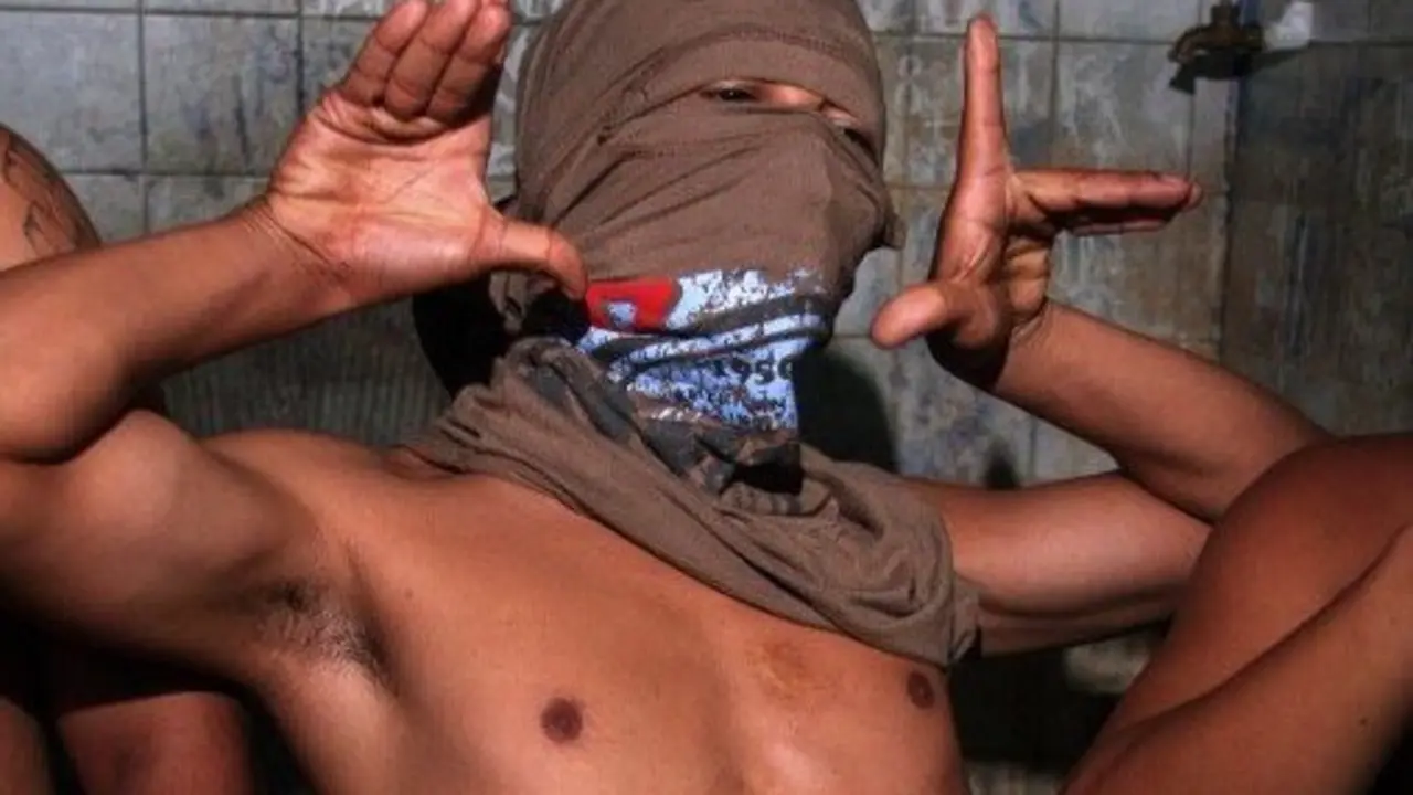 A member of the "Mara 18" juvenile gang makes signs used by the initiated to recognize each other while kept 24 April, 2007 in a cell of the police station of Ilopango, El Salvador, after having been arrested in a raid. Some 200 police members from Central America, Mexico and the US are meeting from Tuesday to Thursday in El Salvador to exchange experiences on the fight against gangs.   AFP PHOTO/Jose CABEZAS / AFP PHOTO / Jose CABEZAS