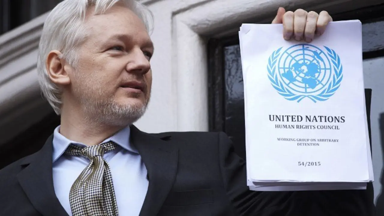 WikiLeaks founder Julian Assange addresses the media holding a printed report of the judgement of the UN's Working Group on Arbitrary Detention on his case from the balcony of the Ecuadorian embassy in central London on February 5, 2016.
During a press conference on February 5 Julian Assange, speaking via video-link, called for Britain and Sweden to "implement" a UN panel finding saying that he should be able to walk free from Ecuador's embassy, where he has lived in self-imposed confinement since 2012. / AFP PHOTO / NIKLAS HALLE'N