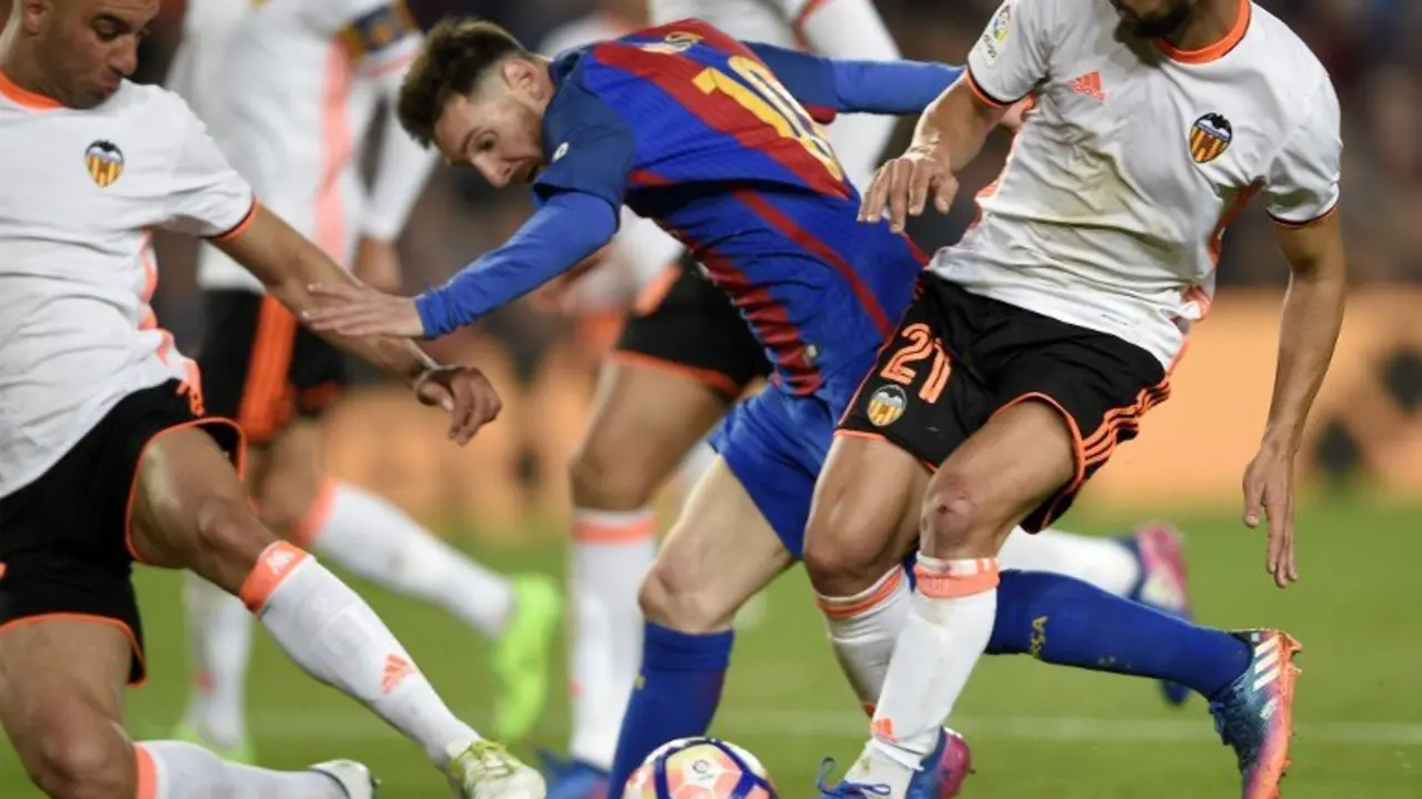 Barcelona's Argentinian forward Lionel Messi (C) vies with Valencia's defender Martin Montoya (R) and Valencia's Tunisian defender Aymen Abdennour (L)  during the Spanish league football match FC Barcelona vs Valencia CF at the Camp Nou stadium in Barcelona on March 19, 2017. / AFP PHOTO / LLUIS GENE
