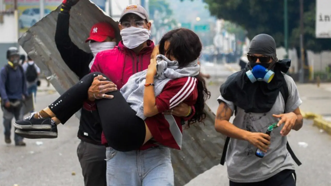 A young woman who was overcome by tear gas shot by tiot police is carried away by fellow demonstrators when opposition activists clashed with riot police in Caracas on April 10, 2017. 
Venezuela's political crisis intensified last week when the Supreme Court issued rulings curbing the powers of the opposition-controlled legislature. The court reversed the rulings days later, but the opposition intensified its protests from that moment.
 / AFP PHOTO / FEDERICO PARRA