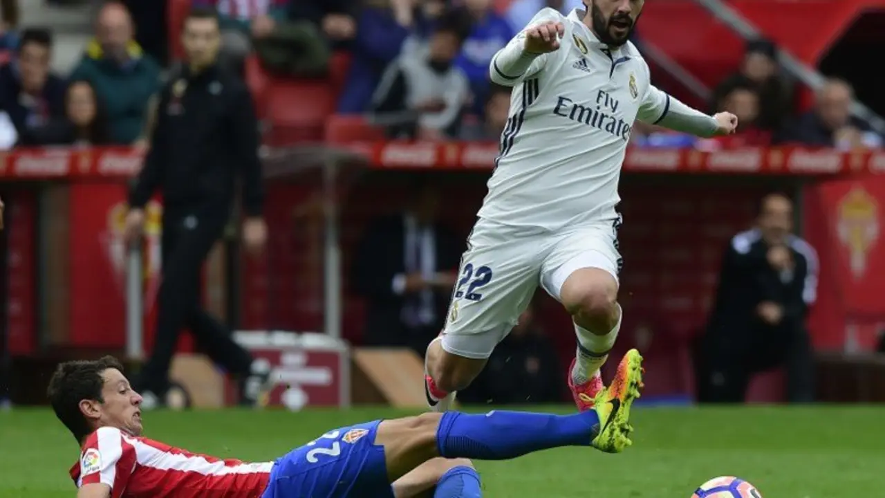 Real Madrid's midfielder Isco (R) controls the ball next to Sporting Gijon's midfielder Mikel Vesga during the Spanish league football match Real Sporting de Gijon vs Real Madrid CF at El Molinon stadium in Gijon on April 15, 2017. / AFP PHOTO / MIGUEL RIOPA