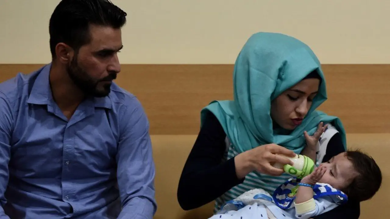 Iraqi mother Gufran Ali (C) is watched by her husband Sarwed Ahmed Nadar as she holds their eight month old son Karam during a press conference at a hospital in Noida on April 14, 2017.
A baby born with eight limbs, including two protruding from his stomach, has undergone surgery in India to successfully remove the extra arms and legs, in an operation being hailed as a world first. Seven-month-old Karam was born in Iraq with an extremely rare condition where a conjoined twin did not fully form and was partially absorbed, resulting in the additional limbs.
 / AFP PHOTO / Money SHARMA