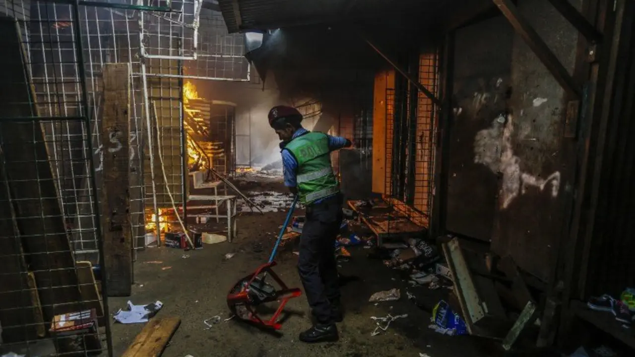 A policeman helps clear the path for firefighters during a fire in the Mercado Oriental, where approximately 25 stores have been completely burned in one of the largest markets in Central America, in Managua on May 14, 2017. / AFP PHOTO / INTI OCON