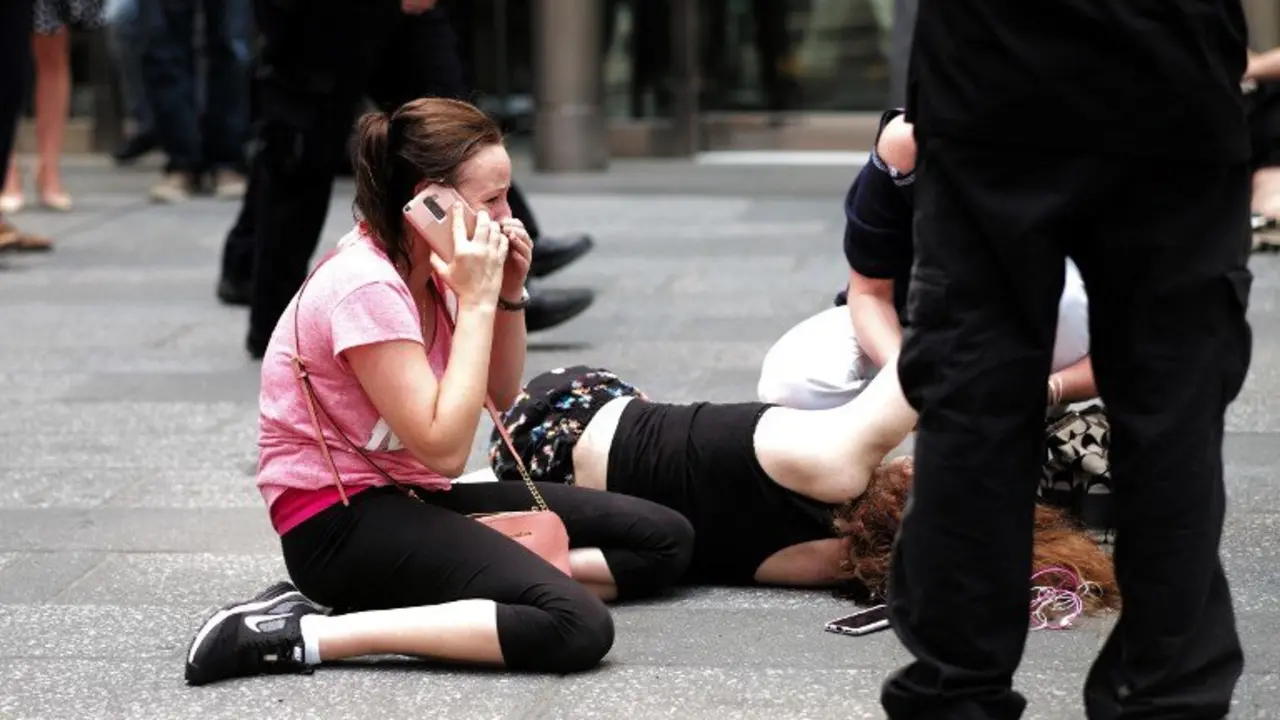 EDITORS NOTE: Graphic content / A woman makes a phone call as others attend to an injured person after a car plunged into them in Times Square in New York on May 18, 2017. 
A car plowed into a crowd of pedestrians in New York's bustling Times Square, leaving one person dead and at least 19 others injured in what officials said was an accident. / AFP PHOTO / Jewel SAMAD