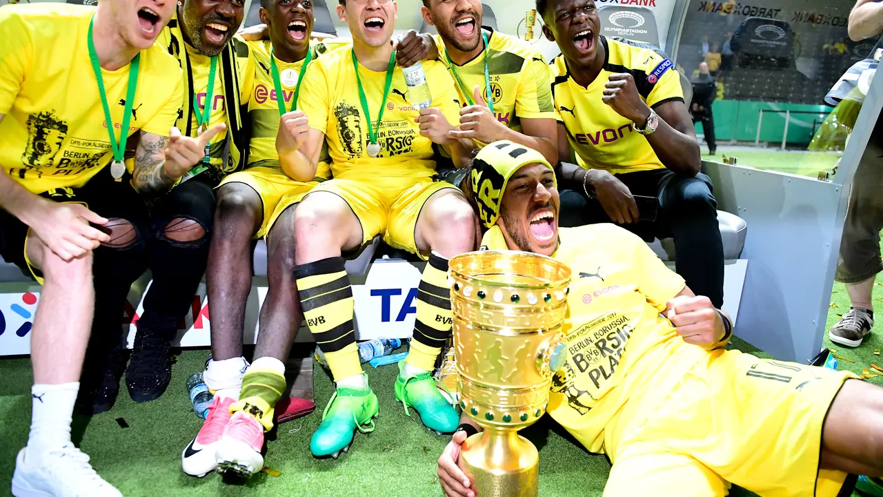 Dortmund's Gabonese forward Pierre-Emerick Aubameyang (front) and teamates celebrate with the trophy after victory during the German Cup (DFB Pokal) final football match Eintracht Frankfurt v BVB Borussia Dortmund at the Olympic stadium in Berlin on May 27, 2017. / AFP PHOTO / Tobias SCHWARZ / RESTRICTIONS: ACCORDING TO DFB RULES IMAGE SEQUENCES TO SIMULATE VIDEO IS NOT ALLOWED DURING MATCH TIME. MOBILE (MMS) USE IS NOT ALLOWED DURING AND FOR FURTHER TWO HOURS AFTER THE MATCH. == RESTRICTED TO EDITORIAL USE == FOR MORE INFORMATION CONTACT DFB DIRECTLY AT +49 69 67880

 / 