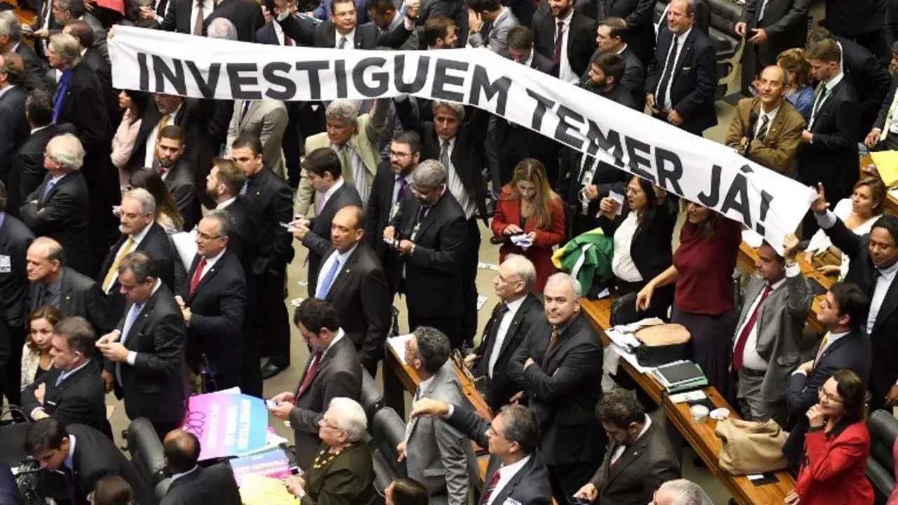 Opposition lawmakers hold a banner reading 'Investigate Temer now!' referring to Brazilian President Michel Temer at the House of Representatives in Brasilia, on August 2, 2017. 
Brazilian lawmakers angrily debated Wednesday ahead of an unprecedented vote on whether President Michel Temer should face trial for alleged corruption, just a year after his predecessor was booted from office. / AFP PHOTO / EVARISTO SA