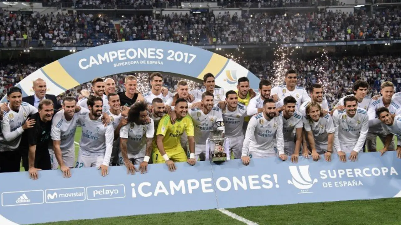 Real Madrid's defender Sergio Ramos (C) holds the trophy as he and teammates celebrate their Supercup after winning the second leg of the Spanish Supercup football match Real Madrid vs FC Barcelona at the Santiago Bernabeu stadium in Madrid, on August 16, 2017. / AFP PHOTO / JAVIER SORIANO