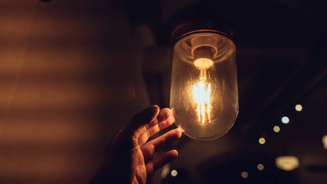 Hand reaching for a vintage light bulb. Dark and abstract concepts