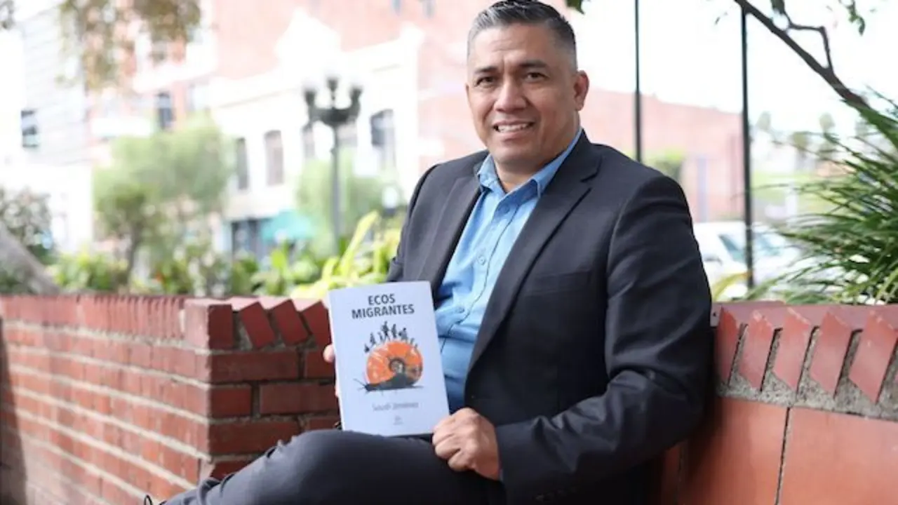 Soudi Jiménez muestra su libro sentado en la emblemática Plaza Olvera en el corazón de la ciudad de Los Ángeles