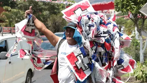 Un hombre recoge varias banderas para adornar los puestos de concentración.