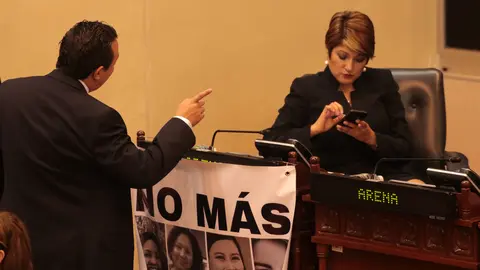 La diputada de ARENA Karla Hernández coloca en su curul una pancarta para reclamar por las mujeres víctimas de violencia.