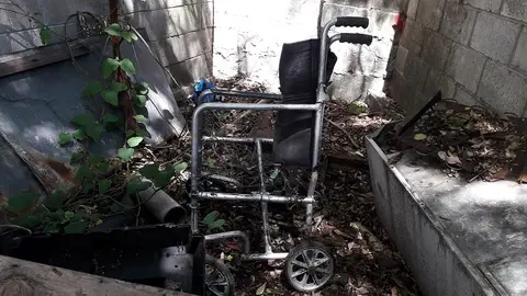 Sillas de ruedas inservibles, camas, archiveros; algunos cubiertos por hojas secas.