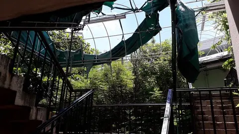 Un toldo quedo destruido durante las fuertes tormentas. Los empleados que suben por las gradas hacia la cocina quedan desprotegidos cuando llueve.