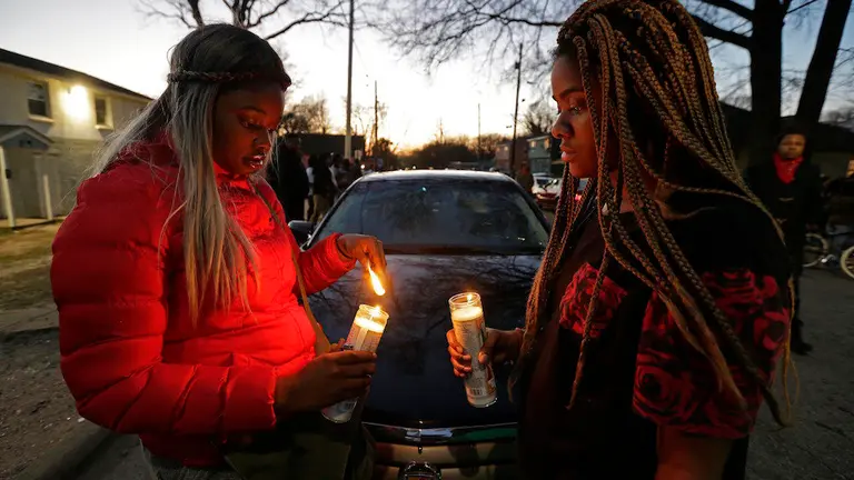 Destiny Brown, left, and Bonnie King light candles during a vigil near the scene of a fatal shooting in Raleigh, N.C., Monday, Feb. 29, 2016. Authorities say that a police officer shot and killed a man while trying to make an arrest for a felony drug charge. (AP Photo/Gerry Broome)