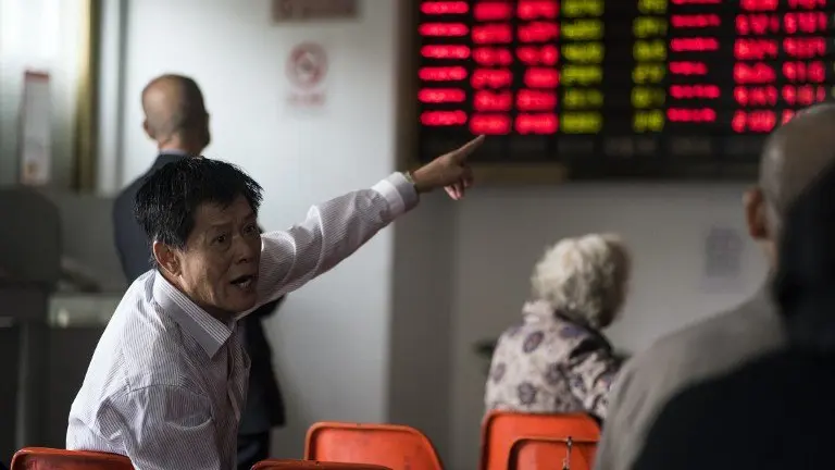 An investor gestures in front of the stock price movements on a screen at a securities company in Shanghai on November 7, 2016. / AFP PHOTO / JOHANNES EISELE