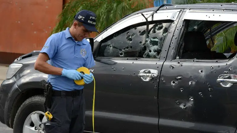 A police officer works beside the bullet-riddled truck the administrator of San Pedro Sula's penitentiary Hugo Hernandez was traveling in when it was attacked by gunmen in a place 180 km north of Tegucigalpa, on November 14, 2016. 
Two other people who were in the vehicle also died in the attack carried out with assault rifles along a  during which more than 300 shots were fired.  / AFP PHOTO / ORLANDO SIERRA