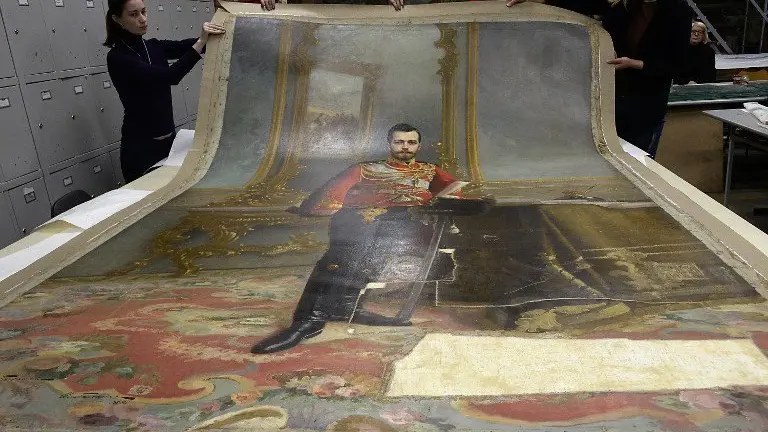 A picture taken in Saint Petersburg on November 17, 2016 shows restorers of the Stieglitz Art and Industry Academy displaying the portrait of Tsar Nicholas II by Ilya Galkin (1896) that was discovered beneath water-soluble paint on the back of the canvas used for the full-size portrait of Vladimir Lenin by Vladislav Izmailovich (1924).
A portrait of the last Tsar of Russia, Nicholas II, remained hidden for nearly a century under a portrait of Soviet state founder Vladimir Lenin, and discovered by chance will soon be exhibited in Saint Petersburg, according to restorers. / AFP PHOTO / Olga MALTSEVA
