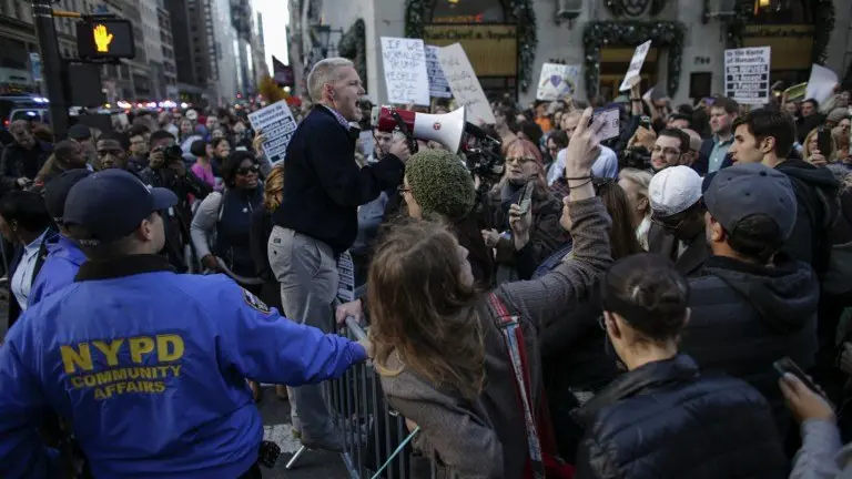 New York Councilman Jimmy Van Bramer (C) shouts slogans as he attends a protest against US President-elect Donald in front of Trump Tower on November 19, 2016 in New York.  / AFP PHOTO / KENA BETANCUR