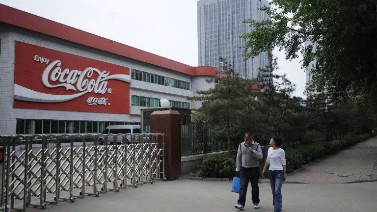 Two workers walk pass the gate of the Coca-Cola Shanxi Beverages Company in Taiyuan, northeast China's Shanxi province on April 30, 2012.  Coca-Cola has been ordered to temporarily halt production at a bottling plant in northern China after media reports of chlorine in its products, according to an April 28, 2012 government statement.  CHINA OUT      AFP PHOTO / AFP PHOTO / STR