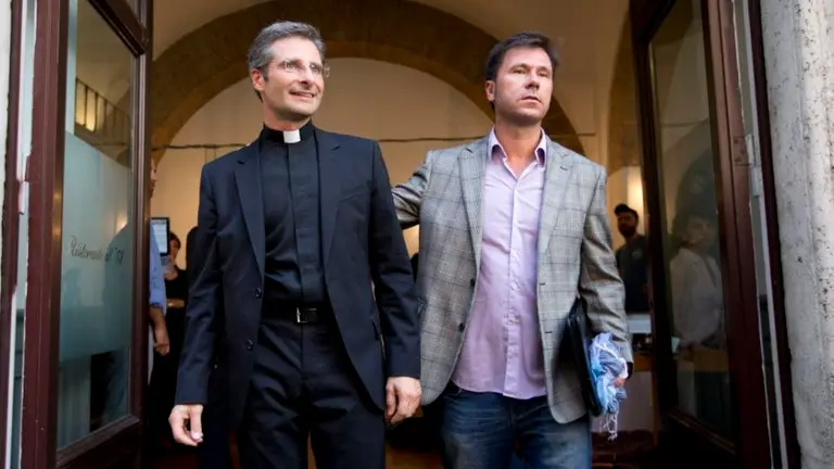 Monsignor Krzysztof Charamsa, left, and his boyfriend Eduard, surname not given, pose for a photo as they leave a restaurant after a press conference in downtown Rome, Saturday Oct. 3, 2015. Vatican on Saturday fired a monsignor who came out as gay on the eve of a big meeting of the world's bishops to discuss church outreach to gays, divorcees and more traditional Catholic families. (AP Photo/Alessandra Tarantino) 