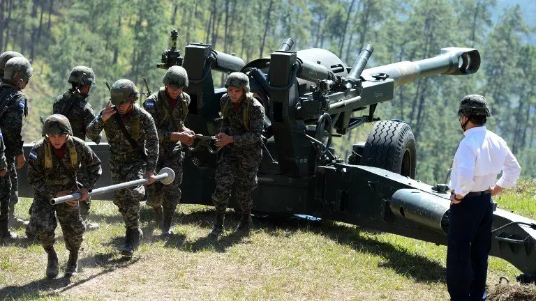 Honduran President Juan Orlando Hernandez (R) prepares to fire a 155mm M 198 howitzer during the Artilleryman Day in Zambrano, 30 km north of Tegucigalpa, on November 29, 2016. / AFP PHOTO / ORLANDO SIERRA