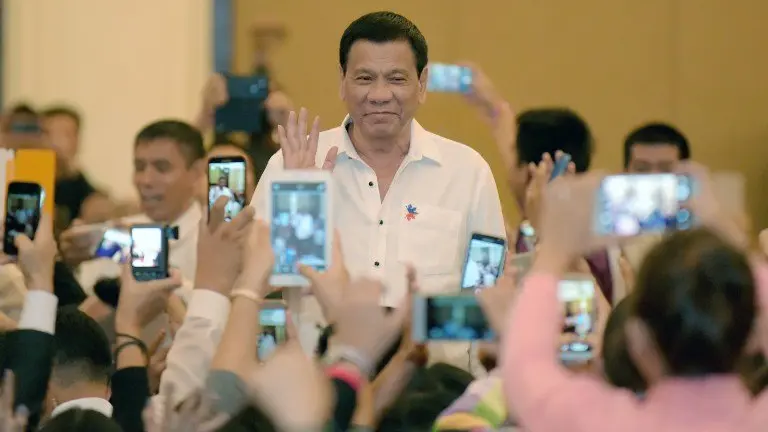 Philippine President Rodrigo Duterte greets members of the Filipino community as he arrives in the Cambodian capital Phnom Penh on December 13, 2016. 
Duterte is on a two-day state visit to Cambodia. / AFP PHOTO / TANG CHHIN SOTHY