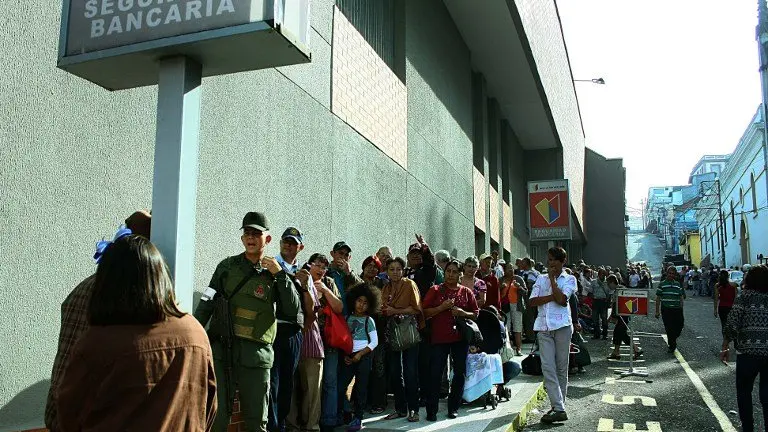 People queue up outside a bank in San Cristobal in an attempt to deposit money, on December 13, 2016. 
Venezuelan President Nicolas Maduro ordered on December 12 the border with Colombia sealed for 72 hours, accusing US-backed "mafias" of conspiring to destabilize his country's economy by hoarding bank notes. The closure came a day after Maduro signed an emergency decree removing Venezuela's largest bank note, the 100 bolivar bill, from circulation because of what he called a Washington-sponsored plot against his country's troubled economy. / AFP PHOTO / George CASTELLANOS