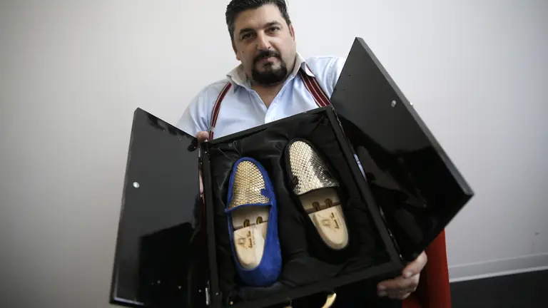 El diseñador italiano Antonio Vietri muestra los zapatos con piezas de oro.