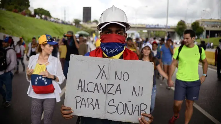 A Venezuelan opposition activist carries a sign reading "we can't even afford to dream anymore", while marching on the freeway in a protest against the government of Nicolas Maduro in Caracas on May 13, 2017.
Daily clashes between demonstrators -who blame elected President Nicolas Maduro for an economic crisis that has caused food shortages- and security forces have left 38 people dead since April 1. Protesters demand early elections, accusing Maduro of repressing protesters and trying to install a dictatorship.
 / AFP PHOTO / FEDERICO PARRA