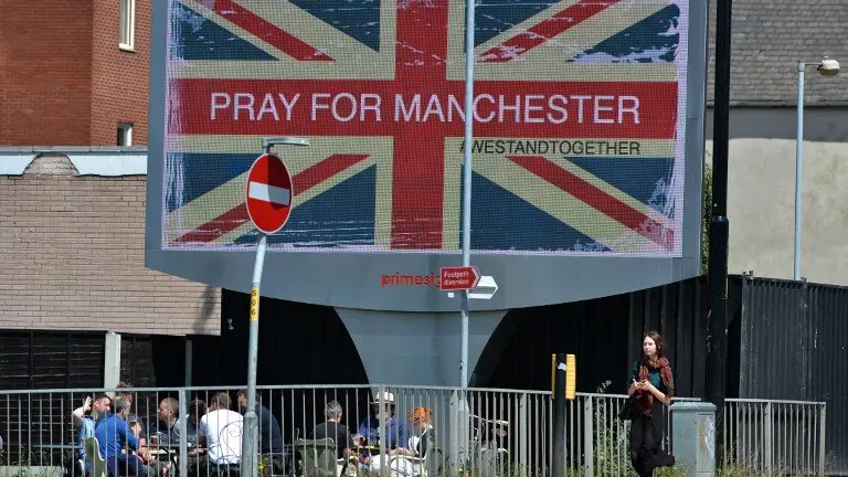 A woman walks past an electronic advertising board displaying a Union flag and the words "Pray For Manchester", close to the Manchester Arena in Manchester, northwest England on May 23, 2017, following a deadly terror attack at an Ariana Grande concert at the Manchester Arena on May 22.
Twenty two people have been killed and dozens injured in Britain's deadliest terror attack in over a decade after a suspected suicide bomber targeted fans leaving a concert of US singer Ariana Grande in Manchester. / AFP PHOTO / Ben Stansall