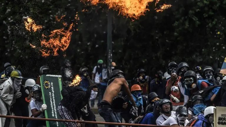 Anti-government protesters blocking the Francisco Fajardo highway in Caracas clash with riot police during a demonstration against Venezuelan President Nicolas Maduro on May 27, 2017.
Demonstrations that got underway in late March have claimed the lives of 58 people, as opposition leaders seek to ramp up pressure on Venezuela&#39;s leftist president, whose already-low popularity has cratered amid ongoing shortages of food and medicines, among other economic woes. / AFP PHOTO / JUAN BARRETO