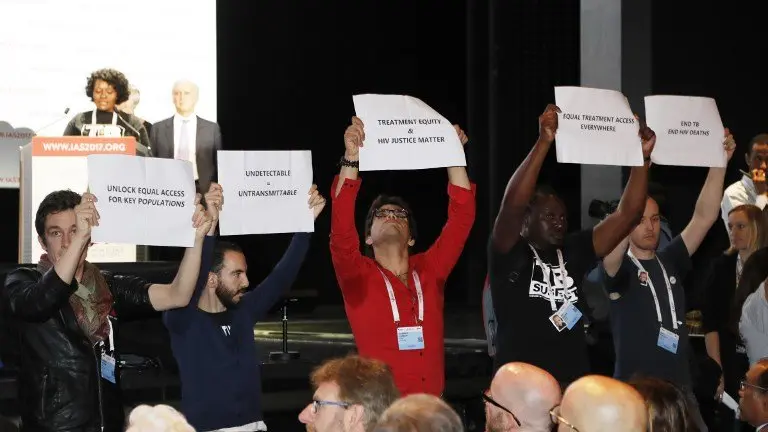 People hold placards during the opening of the 9th International AIDS Society conference on HIV Science on July 23, 2017, in Paris.
More than 6,000 scientists are gathered in the French capital from July 23 to 26, 2017, to assess advances in AIDS science amid concerns over funds drying up. / AFP PHOTO / FRANCOIS GUILLOT