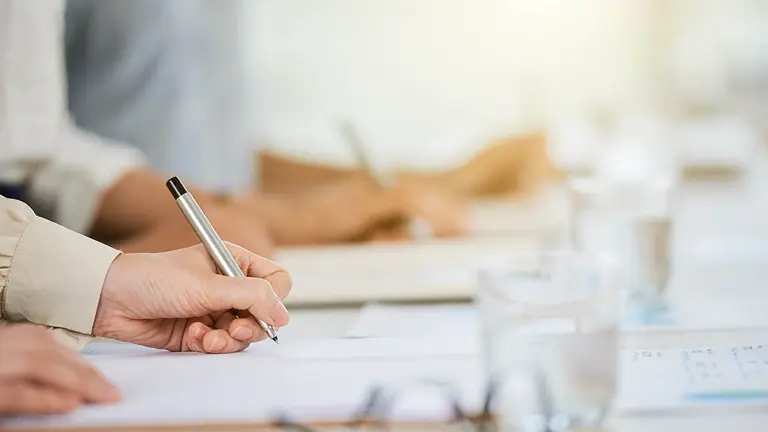 Hand of business lady signing agreement at meeting