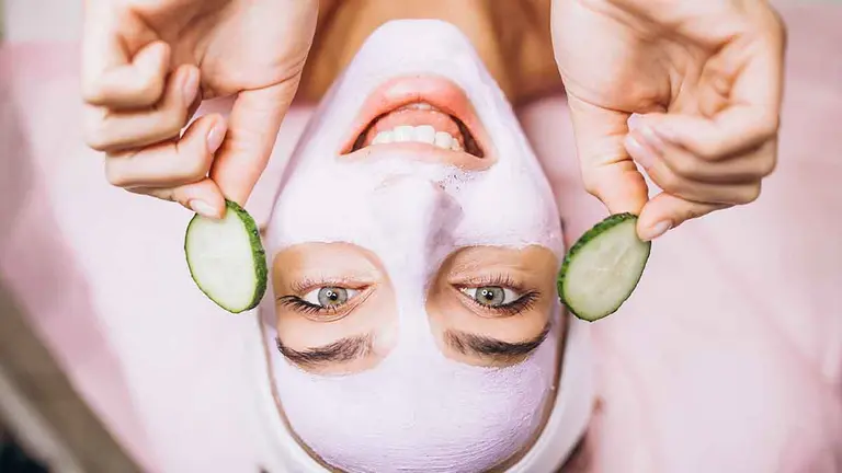 Woman with mask and cucumber on her eyes