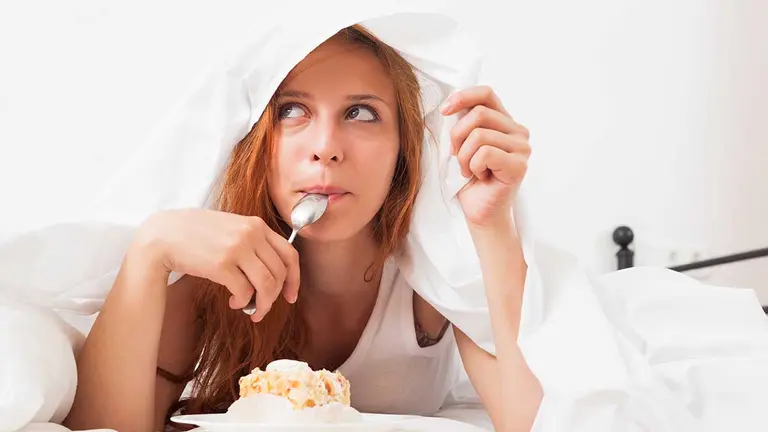 Pretty girl eating biscuit in her bed