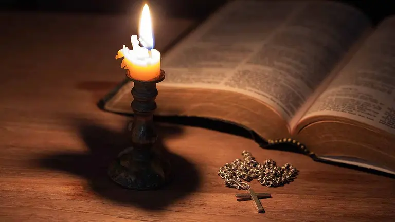 Bible, wood Cross and candles on an old wooden table with a dark background