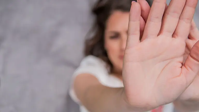 Young woman showing her denial with NO on her hand. Focus on hand. Timid woman symbol of violence in the family