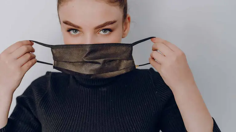 young cozy attractive girl on a light background wears a medical mask. use of personal protection. anti-epidemic and anti-pollution protection of the person.