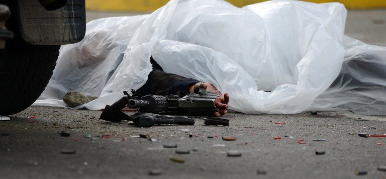 The corpse of the administrator of San Pedro Sula's penitentiary Hugo Hernandez lies on the road alongside the bullet-riddled truck he was traveling in, in a place 180 km north of Tegucigalpa, on November 14, 2016. 
Two other people who were in the vehicle also died in the attack carried out with assault rifles along a  during which more than 300 shots were fired.  / AFP PHOTO / ORLANDO SIERRA