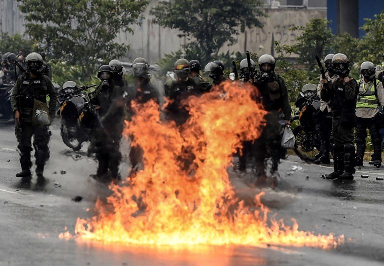 Venezuelan National Guard personnel in riot gear and opposition activists clash in Caracas on April 13, 2017. 
A 32-year-old man died late Thursday after being shot and wounded in a demonstration against President Nicolas Maduro last Tuesday, becoming the fifth victim in the protests that began almost two weeks ago. / AFP PHOTO / JUAN BARRETO