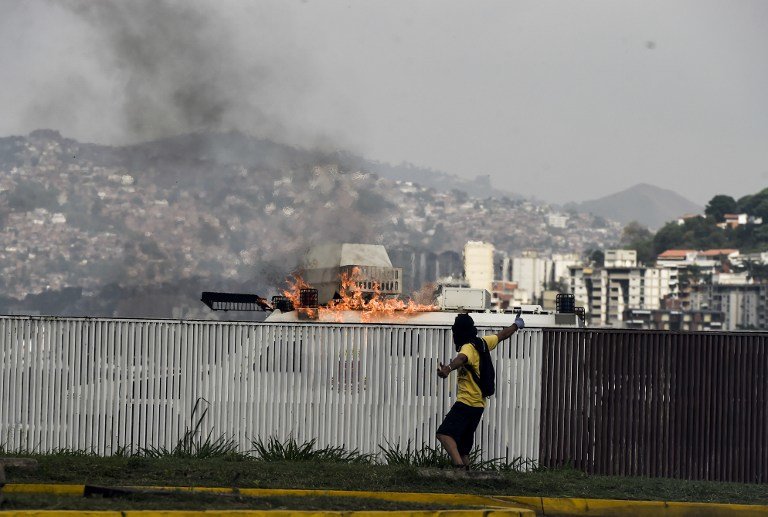 A demonstrator throws a Molotov cocktail at an armored National Guard vehicle during a rally against Venezuelan President Nicolas Maduro, in Caracas on April 19, 2017.
Venezuelans took to the streets Wednesday for massive demonstrations for and against President Nicolas Maduro, whose push to tighten his grip on power has triggered deadly unrest that has escalated the country's political and economic crisis. / AFP PHOTO / JUAN BARRETO